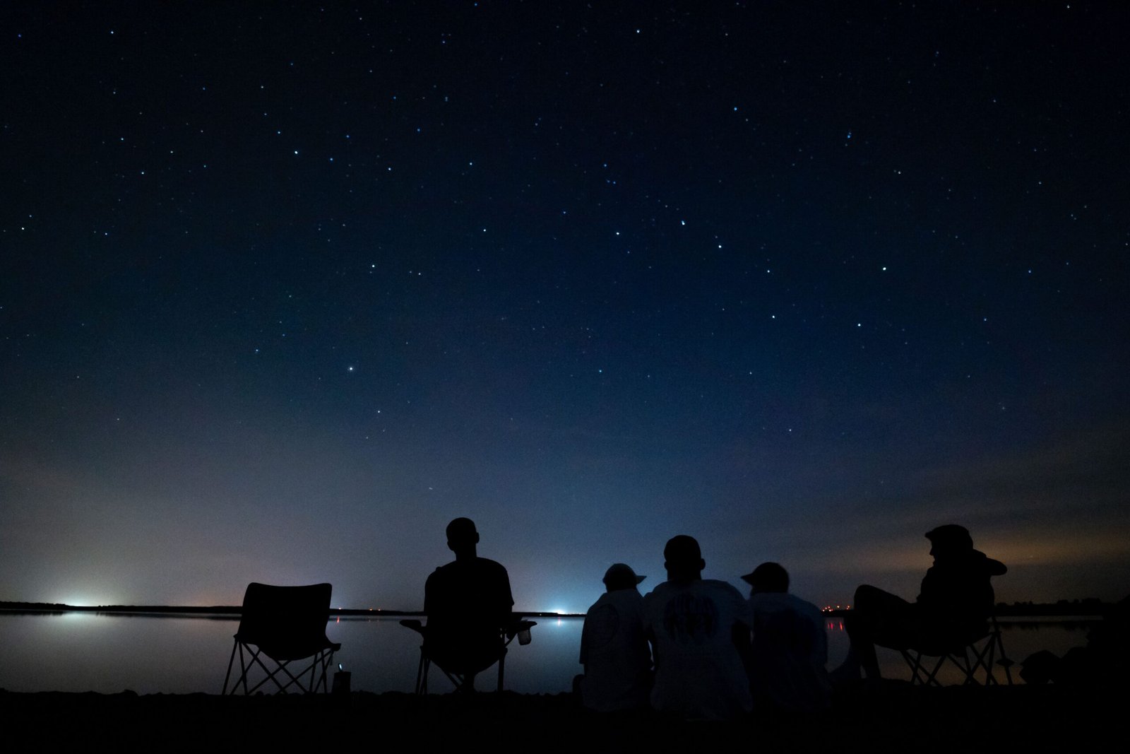 Group of people sitting together observing the night sky filled with stars during a stargazing session